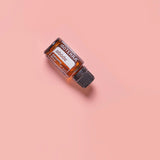 dōTERRA Abode Mischung 15ml – geneigte Flasche auf rosafarbenem Hintergrund | doTERRA