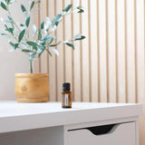 dōTERRA Abode Mischung 15ml – Flasche auf weißem Schreibtisch mit Holzgefäß | doTERRA