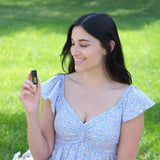 dōTERRA Cheer Mischung 5ml – Frau im blauen Blumenkleid hält Flasche im Garten | doTERRA