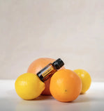 dōTERRA Belebende Mischung (Citrus Bliss) 15ml – Flasche inmitten verschiedener Zitrusfrüchte, beiger Hintergrund | doTERRA