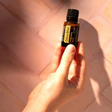 dōTERRA Belebende Mischung (Citrus Bliss) 15ml – Hand hält Flasche auf Mosaik-Terrakottaboden in der Sonne | doTERRA