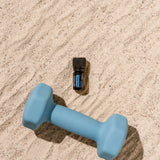 dōTERRA Deep Blue 5ml – Flasche auf Sand neben Hantel, blaues Sonnenlicht, Aufsicht | doTERRA