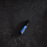 dōTERRA Deep Blue Roll-On 10ml – Flasche liegend auf schwarzem texturierten Granit, Vogelperspektive | doTERRA
