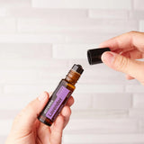 dōTERRA Lavendel Touch Roll-On 10ml – Sich öffnende Hände halten Flasche an weißer Wand | doTERRA