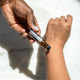 dōTERRA Magnolia Touch Roll-On 10ml – Dunkle Hand wendet Roll-On am Handgelenk auf Marmor an | doTERRA