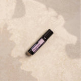 dōTERRA Magnolia Touch Roll-On 10ml – Flasche liegend auf beigem Stein mit Blattschatten | doTERRA
