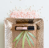 dōTERRA Magnolia Touch Roll-On 10ml – Flasche auf gehämmertem Kupfertablett mit rosa Salz und Blatt | doTERRA
