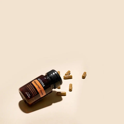 dōTERRA MetaPWR Assist EU Flasche liegend mit Kapseln auf beigem Hintergrund | doTERRA