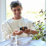 dōTERRA MetaPWR Mito2Max – Mann lächelnd am Holztisch mit Kapseln | doTERRA