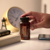 dōTERRA MetaPWR Softgels Hand mit Flasche auf Schreibtisch mit goldener Uhr | doTERRA