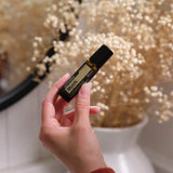 dōTERRA Myrrhe Touch Roll-on 10ml in der Hand mit getrockneten Blumen und unscharfem Schleierkraut-Hintergrund | doTERRA