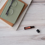 dōTERRA Neroli Touch Roll-on 10ml liegend mit Büchern und Brille auf weißem Holz | doTERRA