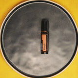 dōTERRA Neroli Touch Roll-on 10ml auf grauem Keramikteller mit gelbem Hintergrund Aufsicht | doTERRA