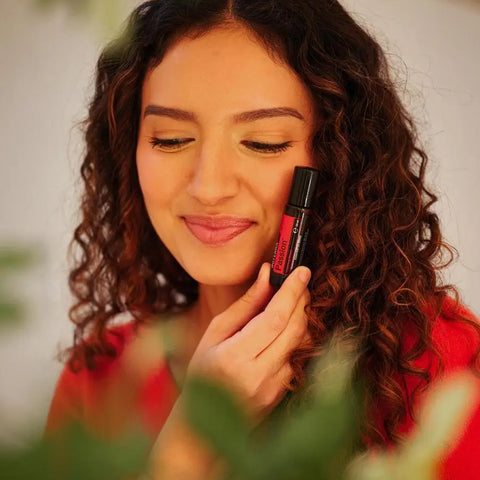 dōTERRA Passion Touch Roll-on 10ml – braunhaarige Frau bei der Anwendung mit Bokeh-Hintergrund | doTERRA