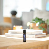 dōTERRA PastTense Roll-on 10ml auf Holztisch mit Büchern und Kerze im Wohnzimmer | doTERRA