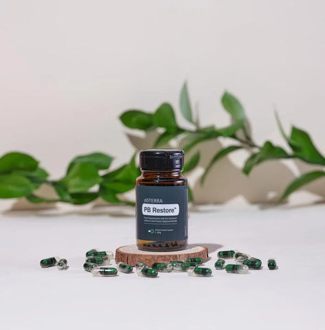 dōTERRA PB Restore – Flasche auf Holzscheibe mit grünen Blättern und Kapseln | doTERRA
