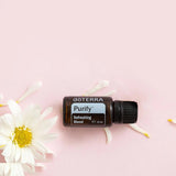 dōTERRA Purify Reinigende Mischung 15ml – Liegend mit Blütenblättern und Gänseblümchen | doTERRA