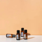 dōTERRA Purify Reinigende Mischung 15ml – Vier gestaffelte Flaschen auf orangefarbenem Hintergrund | doTERRA