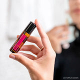 dōTERRA Rosen Touch Roll-on 10ml – Frauenhand hält Flasche drinnen mit Bokeh | doTERRA