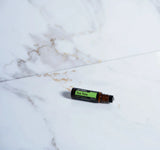 dōTERRA Tea Tree Touch Roll-On liegend auf weißem Marmor mit Gold | doTERRA