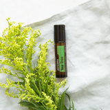 dōTERRA Tea Tree Touch Roll-On Aufsicht mit gelben Blumen und weißem Leinen | doTERRA