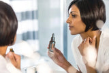dōTERRA Yarrow Pom 30ml Frau vor Spiegel im Bad, Anwendung am Nacken mit Pipette | doTERRA