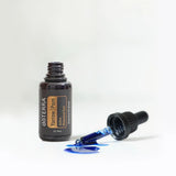 dōTERRA Yarrow Pom 30ml offene Flasche mit Pipette und verschüttetem Öl auf Blau | doTERRA