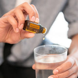 dōTERRA Zendocrine Mischung 15ml – Hände bringen Tropfen in Wassergefäß auf, Nahaufnahme | doTERRA