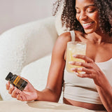 dōTERRA Zendocrine Softgels lockige Frau mit schwarzer Flasche auf dem Sofa | doTERRA